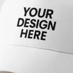 Șapcă personalizată albă – prim-plan pe inscripție frontală cu text negru „Your Design Here”, material texturat, ideală pentru branding