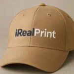 Șapcă crem personalizată cu nume și text – detaliu logo iRealPrint, design clar și elegant