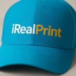 Șapcă turcoaz personalizată cu text iRealPrint, logo imprimat alb și auriu