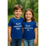 tricou copii personalizat albastru regal – frate și soră purtând tricouri cu mesaje “Sunt supereroul tău” și “Sunt supereroina ta”, fundal verde natural
