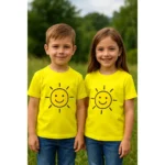Tricou copii personalizat galben lămâie iRealPrint – băiat și fată purtând tricouri cu imprimeu soare zâmbitor, fundal natural verde, culoare galben intens, stil vibrant și jucăuș.