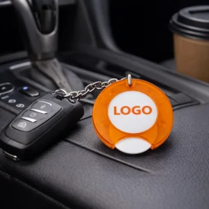 Prim-plan breloc cu fisă de cumpărături personalizat portocaliu, detaliu logo print color pe suprafață rotundă, accent pe vizibilitate și impact promoțional