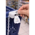 Breloc cu fisă din plastic alb personalizat folosit la cărucior în supermarket, exemplu real de utilizare zilnică pentru expunere constantă a brandului