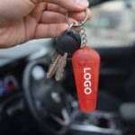 Breloc roșu cu fluier și lanternă prins la chei, scenă de utilizare reală pentru activități zilnice și coordonare rapidă