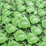 Breloc promoțional verde cu fisă pentru cărucior în cantitate mare, ideal pentru campanii de branding și fidelizare
