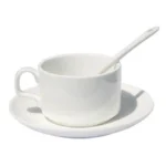 Set ceașcă cafea personalizată cu linguriță și farfurie prezentat pe fundal alb minimalist, evidențiind designul elegant al setului ceramic complet