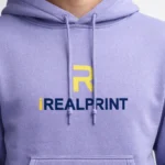 Detaliu apropiat hanorac violet personalizat cu logo contrastant aplicat, evidentiind claritatea printului si finisajul premium