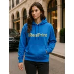 Model feminin purtând hanorac albastru sapphire personalizat iRealPrint într-un cadru urban elegant, look premium
