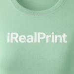 Model feminin purtând tricou damă personalizat sage într-un cadru urban modern, evidențiind stilul casual și personalizarea cu logo