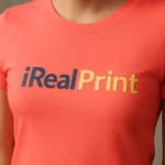 Detaliu personalizare logo iRealPrint aplicat prin transfer termic pe tricou damă personalizat coral, imprimare clară cu contrast puternic