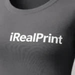 Detaliu logo iRealPrint aplicat prin transfer termic pe bluză damă gri metalic, material premium și contrast elegant pe fundal modern