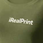 Detaliu logo iRealPrint aplicat prin transfer termic pe bluză damă kaki, material din bumbac premium și contrast vizual clar pe fundal natural