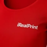 Detaliu logo iRealPrint aplicat prin transfer termic pe bluză damă roșie, material premium din bumbac și contrast vizual puternic