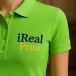 Detaliu personalizare logo iRealPrint aplicat prin transfer termic pe tricou polo damă personalizat verde măr, evidențiind claritatea printului și textura materialului