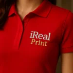 Detaliu personalizare logo iRealPrint aplicat pe tricou polo damă personalizat roșu, evidențiind claritatea transferului termic și textura materialului