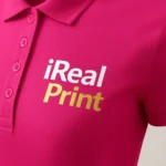 Detaliu personalizare logo iRealPrint aplicat prin transfer termic pe tricou polo damă personalizat purpuriu, evidențiind claritatea printului și textura materialului