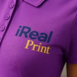 Detaliu personalizare logo iRealPrint pe tricou polo damă mov realizată prin transfer termic profesional cu contrast puternic