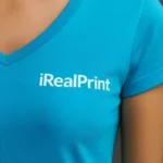Detaliu personalizare logo pe tricou damă turcoaz cu anchior în V, transfer termic clar aplicat pe material din bumbac premium