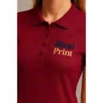Detaliu logo iRealPrint aplicat prin transfer termic pe tricou polo damă garnet, evidențiind textura materialului și contrastul personalizării