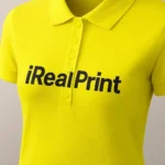 Detaliu logo iRealPrint aplicat prin transfer termic pe tricou polo damă galben lămâie, personalizare clară cu contrast puternic