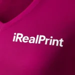 Detaliu personalizare logo pe tricou damă roșu fucsie cu anchior în V, transfer termic clar aplicat pe material bumbac premium