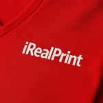 Detaliu personalizare logo pe tricou damă roșu cu anchior în V, transfer termic clar aplicat pe material din bumbac premium