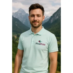 Bărbat purtând tricou polo bărbați personalizat culoare frost cu logo iRealPrint într-un peisaj montan, stil modern pentru branding profesional și imagine corporate
