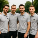 Echipă de bărbați purtând tricouri polo personalizate gri deschis cu logo iRealPrint, uniforme moderne pentru branding corporate și imagine profesională