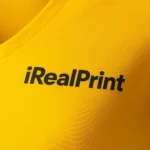 Detaliu personalizare logo pe tricou damă galben cu anchior în V, transfer termic clar aplicat pe material bumbac premium