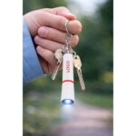 Breloc lanternă roșu personalizat prins la chei, scenă lifestyle cu utilizare reală și lumină LED activă pentru vizibilitate imediată