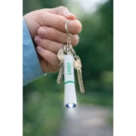 Breloc lanternă verde personalizat prins la chei, scenă lifestyle cu utilizare reală, obiect promoțional practic pentru activități zilnice