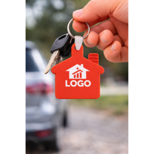 Breloc promoțional roșu în formă de casă folosit la chei, imagine lifestyle ce transmite energie și utilizare zilnică