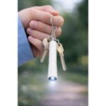 Breloc cu lanternă LED albă prins de chei în utilizare reală, accesoriu promoțional util pentru iluminare rapidă și branding zilnic