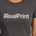 Detaliu personalizare logo iRealPrint aplicat prin transfer termic alb pe tricou damă personalizat gri metalic, evidențiind claritatea și contrastul printului