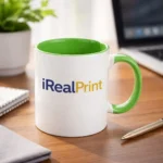 Cană personalizată cu interior verde lime și logo iRealPrint plasată pe birou într-un cadru de lucru modern, sugerând utilizarea zilnică în spații office