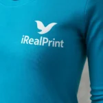 Detaliu bluză damă turcoaz cu logo iRealPrint aplicat prin transfer termic clar și durabil