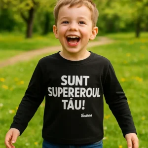 Copil purtând bluză neagră personalizată cu mesaj Sunt Supereroul Tău în timpul jocului în parc