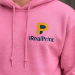 Detaliu hanorac personalizat bărbați roz azalea cu logo iRealPrint aplicat pe piept, evidențiind textura materialului și calitatea personalizării grafice