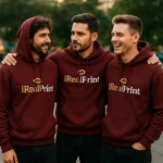 Grup de bărbați purtând hanorace personalizate maroon bordo cu logo iRealPrint, stil urban streetwear modern pentru echipe, branding vizibil și identitate de brand puternică