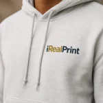 Detaliu hanorac bărbați ash gri deschis cu logo iRealPrint aplicat prin transfer termic profesional, personalizare clară și durabilă pentru branding premium