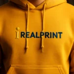 Detaliu hanorac bărbați gold cu logo iRealPrint aplicat prin transfer termic profesional, evidențiind contrastul puternic al personalizării și claritatea designului pe material premium