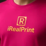 Detaliu close-up cu logo iRealPrint imprimat prin transfer termic pe tricou unisex purpuriu, evidențiind claritatea personalizării