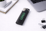Brichetă slim personalizată negru cu logo verde prezentată pe birou alături de laptop și accesorii office, produs promoțional elegant pentru branding corporate și utilizare zilnică.