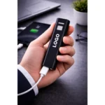 Baterie externă personalizată neagră în cadru lifestyle de birou, power bank premium cu logo pentru companii, evenimente business și cadouri corporate