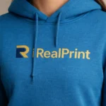 Close-up pe hanorac albastru sapphire cu logo iRealPrint, accent pe detalii și lizibilitate maximă