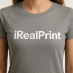 Detaliu personalizare logo iRealPrint aplicat prin transfer termic alb pe tricou damă personalizat gri închis, evidențiind claritatea și contrastul printului