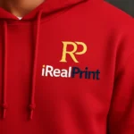 Detaliu hanorac personalizat bărbați roșu cu logo iRealPrint aplicat pe piept, evidențiind textura materialului și calitatea personalizării grafice