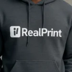 Detaliu hanorac bărbați dark heather cu logo iRealPrint aplicat prin transfer termic profesional, evidențiind claritatea printului, contrastul puternic și aspectul premium al personalizării