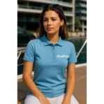 Model feminin purtând tricou polo damă personalizat albastru azur într-un cadru urban modern, sugerând utilizarea pentru branding profesional și stil business-casual