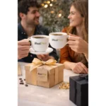 Set ceașcă cafea personalizată cu linguriță și farfurie și logo iRealPrint oferit cadou unui cuplu într-un cadru festiv, sugerând un moment special împărtășit